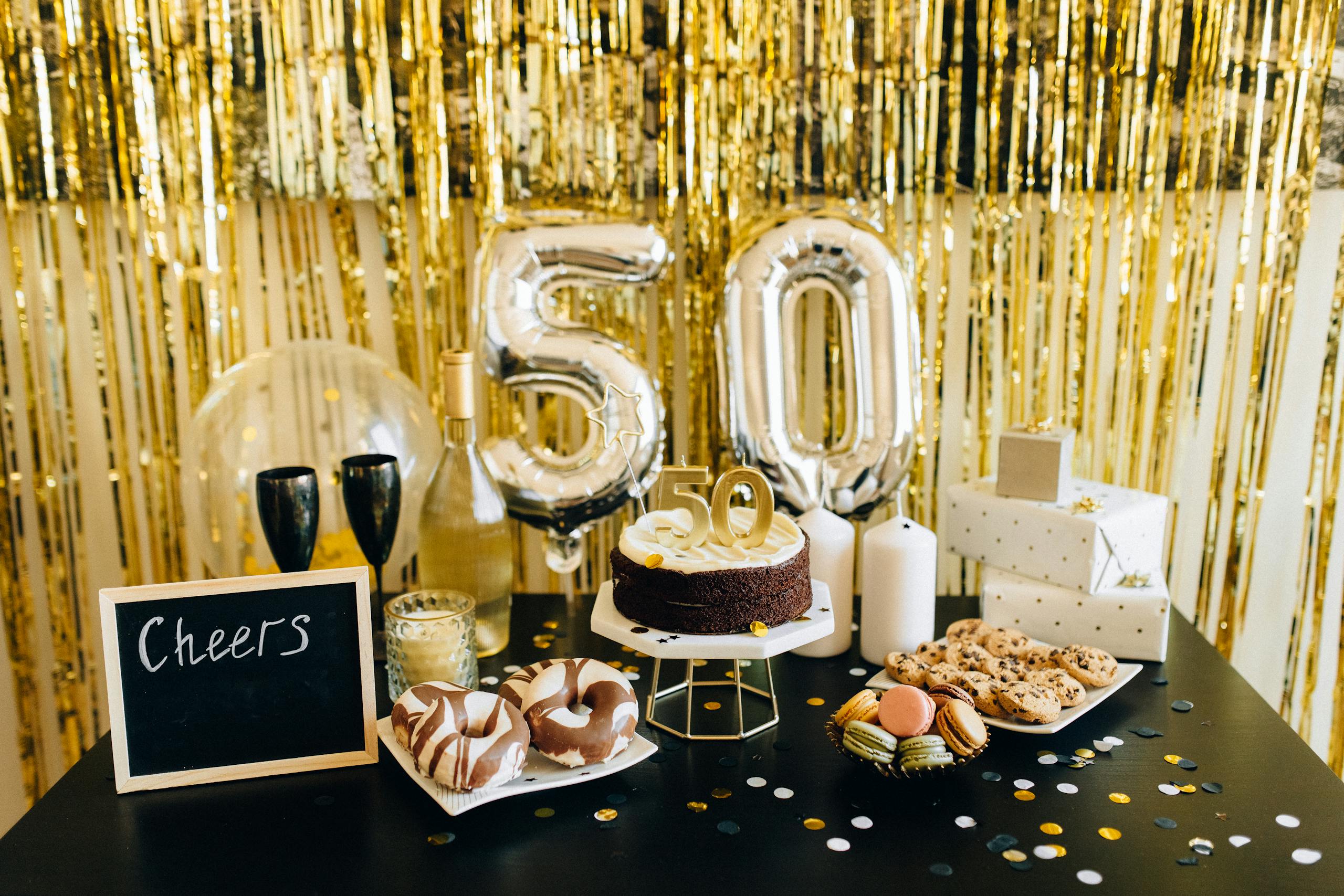 Stylish 50th birthday party setup with cake, balloons, gifts, and champagne amidst golden decorations.